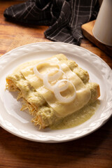 Mexican food. Enchiladas with creamy green sauce filled with shredded chicken meat and covered with melted cheese, in Mexico they are called Swiss Enchiladas. Very popular recipe in Mexican cuisine.