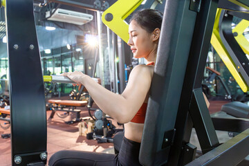 Asian woman working out in the gym, Young fitness women execute exercise with exercise-machine in the gym