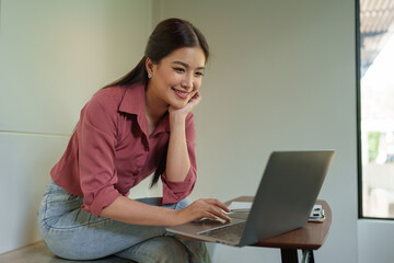 Happy Asian businesswoman on balcony using laptop to do morning work Business woman on holiday working outside that is natural Beautiful blogger woman thinking about content for work.