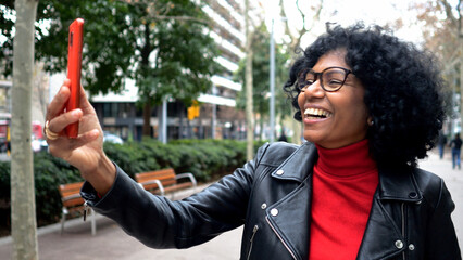Middle-aged African American woman in a city making a video call in a city with a mobile phone
