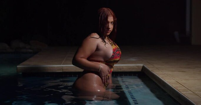 Against the backdrop of the night sky, a girl in a bikini relishes the peaceful serenity of the poolside retreat.