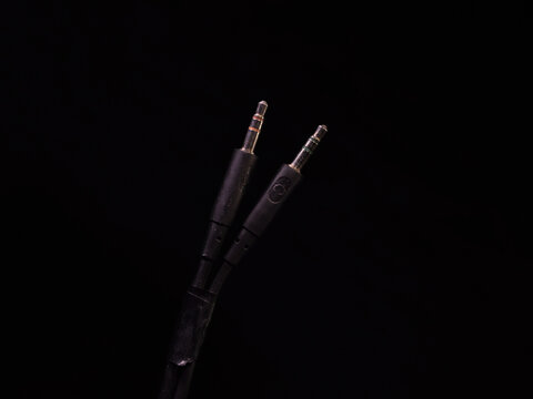Close-up view of gold-plated audio and microphone cables on a black studio background.