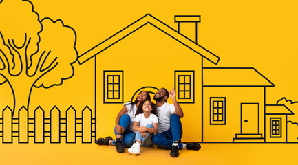 Dreaming African American family father mother and child sitting on floor over drawn on yellow wall house. Mortgage, real estate concept © Prostock-studio