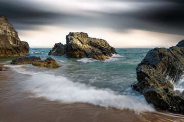 Long exposure photo of waves and rocks on an overcast day.