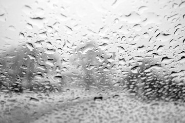 View on winter city through wet windshield with rain drops. Black and white