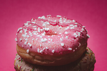 Glazed donut with sugar sprinkles clean pink background.