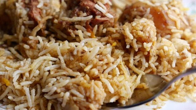 spoon pick mutton biryani meal in a plate on table.