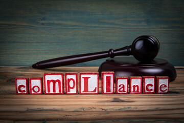 COMPLIANCE. Red alphabet letters and judge's gavel on wooden background. Laws and justice concept