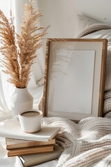 Empty picture frame, modern vase and coffee on stack of books.