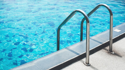 Chrome handrails of the swimming pool. Hotel spa and resort accommodation. Ladder on the poolside....