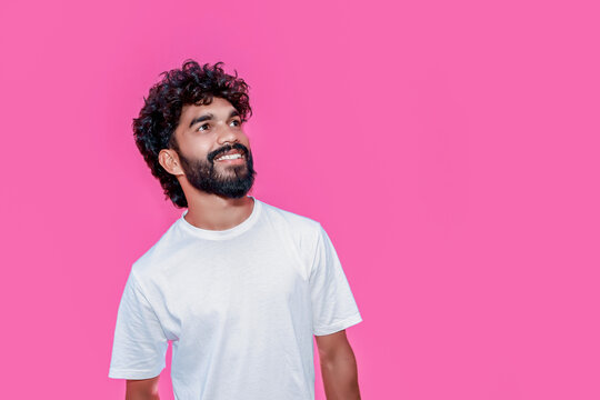 Handsome joyful smiling young indian man looking aside up and straight thinking of new good opportunities, dreaming, feeling inspired and proud standing isolated on pink background. Portrait
