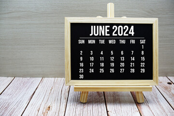 June 2024 monthly calendar on easel stand on wooden background