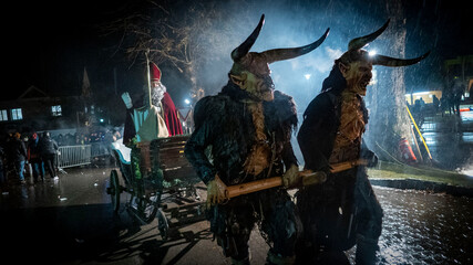 Krampusse ziehen den Nikolaus auf seinem Schlitten