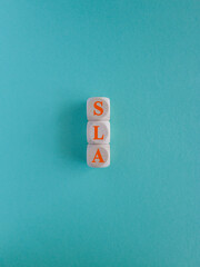 SLA service level agreement symbol. Concept words SLA on wooden cubes. Beautiful blue background....