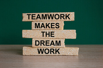 Concept words Teamwork makes the dream work on brick blocks on a beautiful wooden table, green...