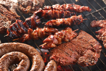 grilled meat on the grill. South African braai meat including Boerewors, chicken kebabs, chops and...