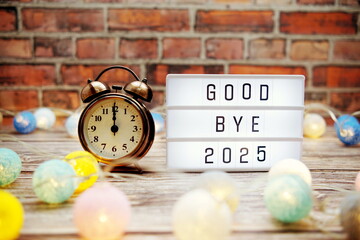 Goodbye 2025 text in light box with alarm clock and LED cotton balls decoration
