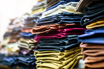 Lots of clothes folded and stacked on shelves in a clothing store.