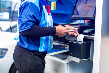 The cashier was pulling a fuel slip from the teller machine. Post of sale, POS.