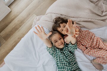 portrait of two girls lying on the bed and posing for a photo after just waking up and stretching...