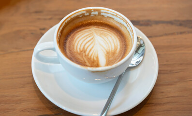 Hot latte art coffee cup on wooden table