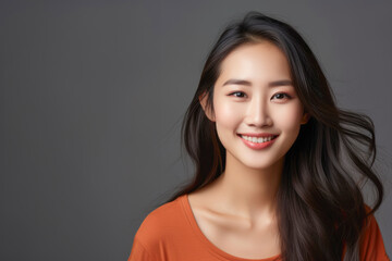 Fototapeta premium Gorgeous young asian woman in an orange top smiling