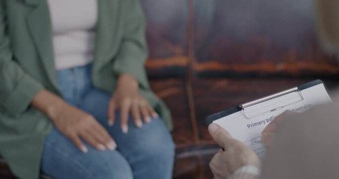 Close-up of hands therapist writing taking notes while client talking discussing problem indoors in office. Therapy and appointment concept.