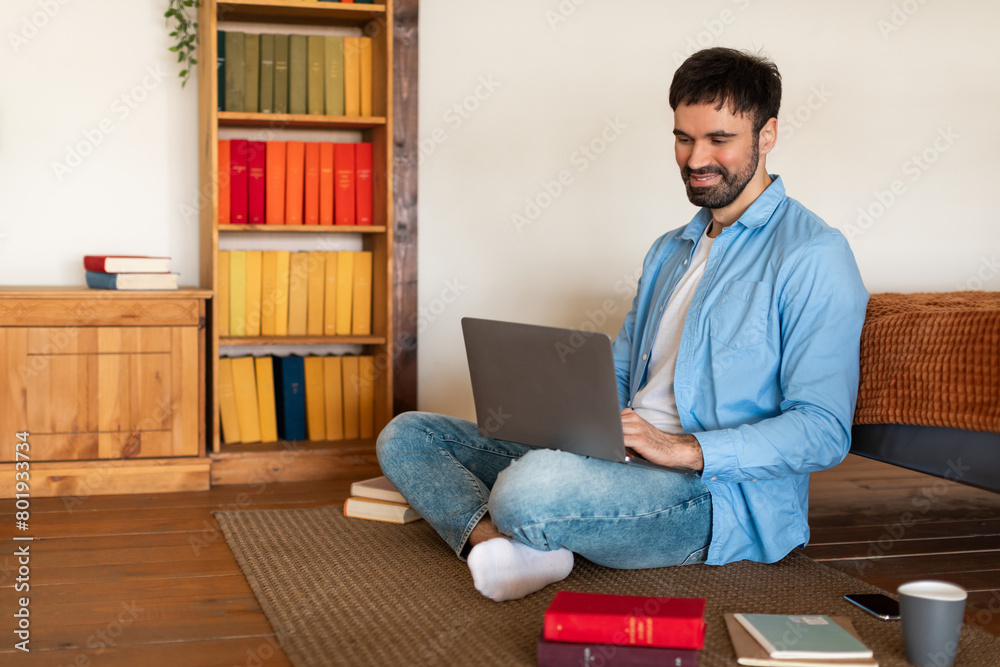 Aufkleber a man is seated on the floor, typing on a laptop in front of him. he appears focused and engaged wit
