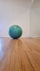 Green exercise ball on wooden floor in modern interior