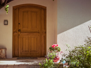 A contemporary design house entrance with an arched wooden door by a green garden. Travel to...