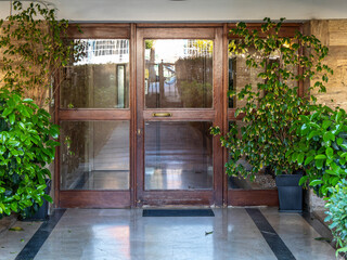 A contemporary design house entrance with a wooden door and decorative plants. Travel to Athens,...