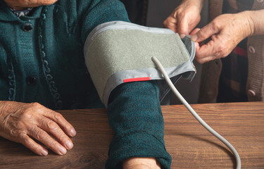 Measuring blood pressure of elderly woman at home.