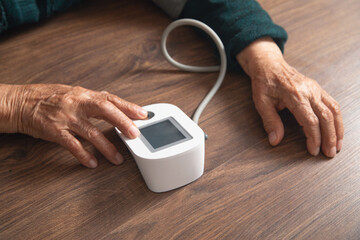 Measuring blood pressure of elderly woman at home.