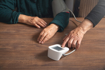 Fototapeta na wymiar Measuring blood pressure of elderly woman at home.