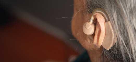 Caucasian elderly woman with a hearing aid in ear.