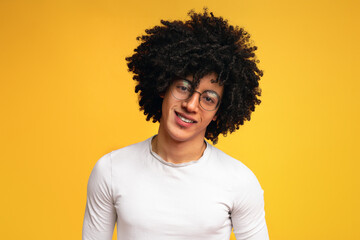 Portrait of black guy in glasses with bushy hairstyle, orange studio background, panorama with...