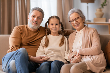 A heartwarming scene captures a young girl seated between her grandparents, sharing a moment of joy at home interior