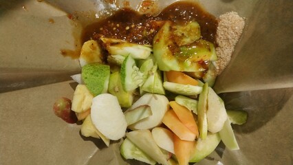 Rujak buah or indonesian mixed fruit salad, served with spicy brown sugar sauce and ground peanuts