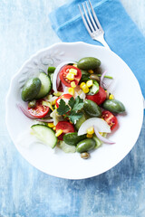 Simple Salad with Green and Kalamata Olives, Cucumber, Cherry and marinated Tomatoes, Capers and Jalapeno Pepper. Bright wooden background. Top view.