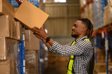 Portrait of black man worker working in large warehouse retail store industry factory. Rack of...