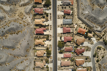 An aerial photograph illustrating the process of desertification, with urban residential areas surrounded by encroaching desert.


