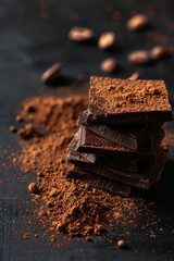 Stacked Chocolates and Cocoa Powder on Dark Background