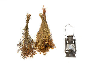 vintage still life of dried herbs and a lamp with a candle isolated on white background