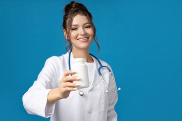 Attractive young girl in doctor's gown with stethoscope and pills