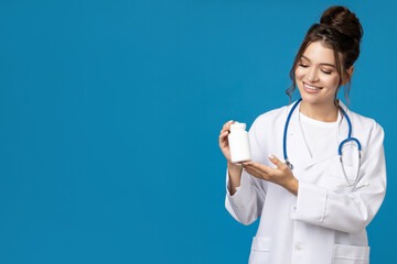 Attractive young girl in doctor's gown with stethoscope and pills