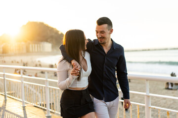 Romantic couple embracing walking along a promenade during sunset