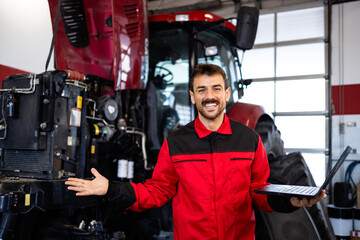 Portrait of professional mechanic with diagnostic tool servicing tractor machine.