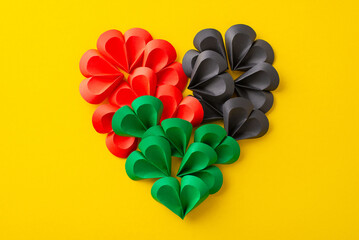 Overhead shot of miniature paper hearts arranged to create a grand heart shape, mirroring the hues...