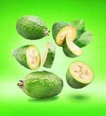 Falling down feijoa fruits and slices of feijoa isolated on green background.