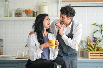 Cheerful loving couple enjoying morning coffee at home, happy spouses having conversation, standing in house